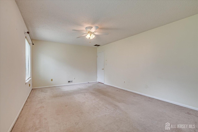 carpeted empty room with baseboards, a ceiling fan, a textured ceiling, and visible vents