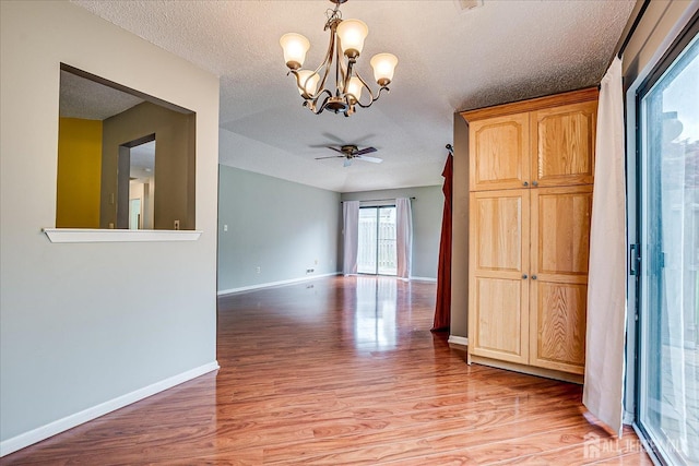 unfurnished room with baseboards, a textured ceiling, light wood finished floors, and ceiling fan with notable chandelier