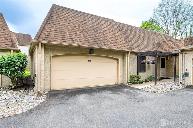 view of front of house featuring an attached garage, aphalt driveway, roof with shingles, and stucco siding