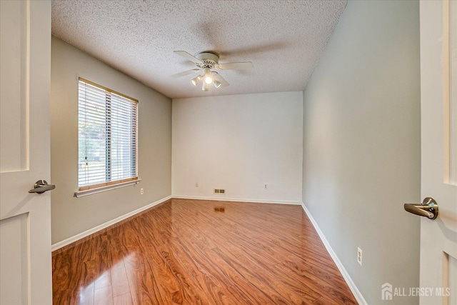 unfurnished room featuring visible vents, wood finished floors, baseboards, ceiling fan, and a textured ceiling