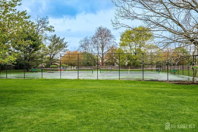 view of sport court with fence and a yard