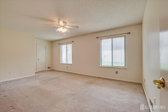 empty room featuring light colored carpet, a textured ceiling, ceiling fan, and baseboards