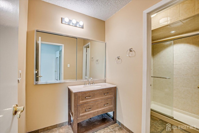 bathroom with vanity, a textured ceiling, baseboards, and a shower stall