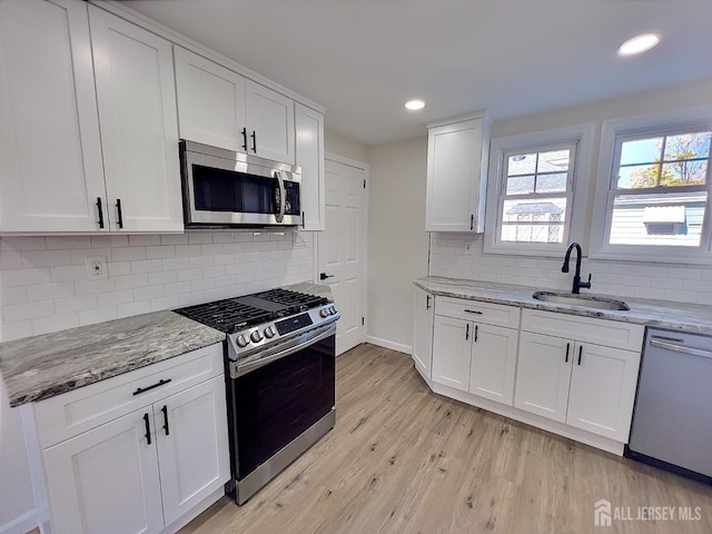 kitchen featuring white cabinetry, sink, stainless steel appliances, and light wood-type flooring