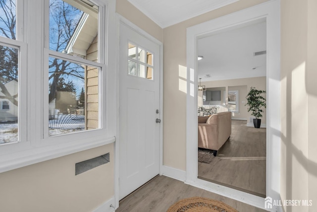 foyer entrance with baseboards, visible vents, and wood finished floors