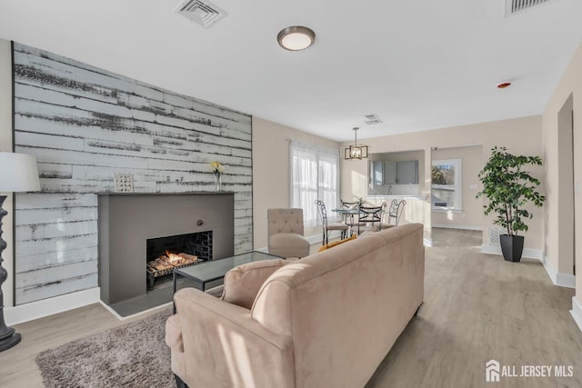 221 E Golf Ave, South Plainfield, NJ 07080 - living room with light wood-type flooring, a lit fireplace, baseboards, and a chandelier