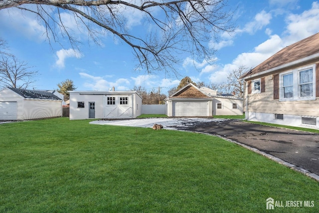 view of front of house featuring driveway, a front yard, an outbuilding, a detached garage, and stucco siding