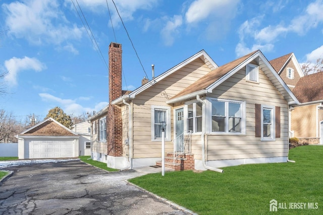 view of front of property with an outbuilding, a chimney, a front yard, and a garage