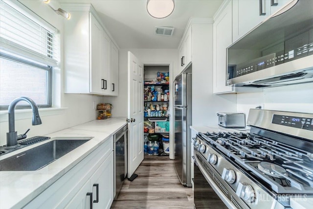 111 Beverly Hill Ter Unit A, Woodbridge Proper, NJ 07095 - kitchen featuring stainless steel appliances, a sink, white cabinetry, light stone countertops, and light wood-style flooring