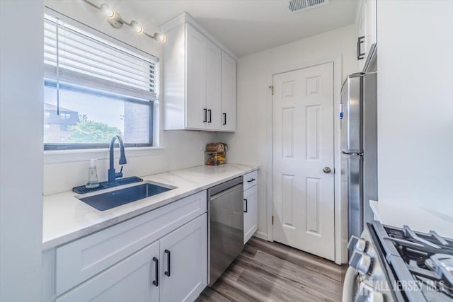 111 Beverly Hill Ter Unit A, Woodbridge Proper, NJ 07095 - kitchen with stainless steel appliances, a sink, white cabinets, light stone counters, and wood finished floors
