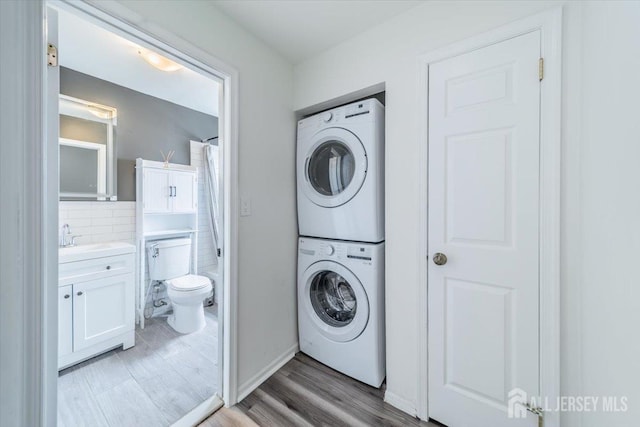 111 Beverly Hill Ter Unit A, Woodbridge Proper, NJ 07095 - laundry area featuring stacked washing machine and dryer, light wood-type flooring, and baseboards