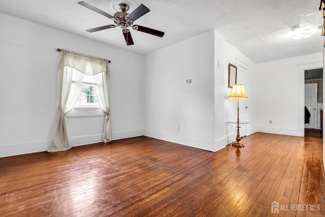 empty room featuring wood-type flooring, ceiling fan, baseboards, and a textured ceiling