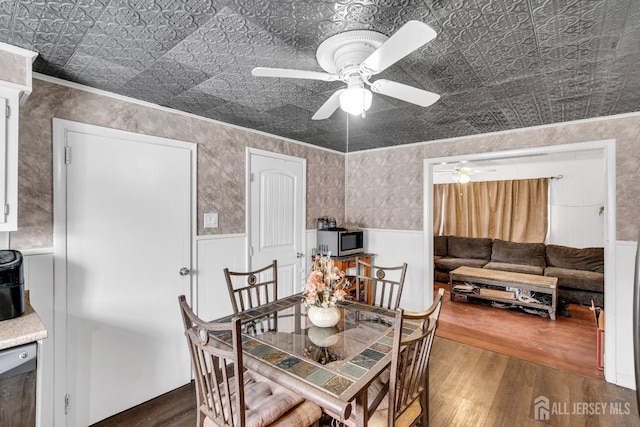 dining space with an ornate ceiling, wood finished floors, a ceiling fan, wainscoting, and crown molding