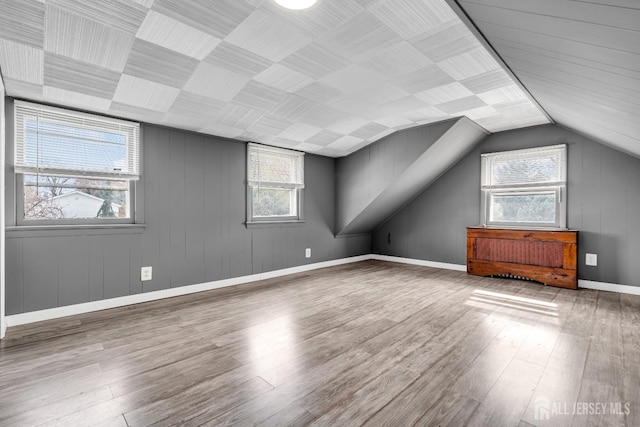bonus room with wood finished floors, vaulted ceiling, and baseboards