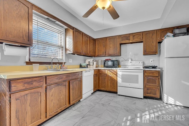 kitchen featuring brown cabinetry, white appliances, ceiling fan, light countertops, and a sink