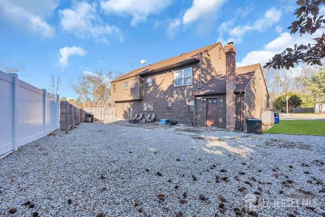 rear view of property with a chimney and a fenced backyard