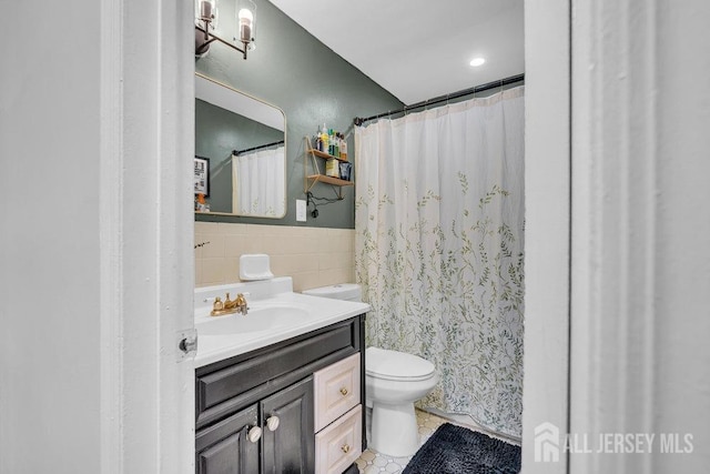 bathroom with tile walls, wainscoting, vanity, tile patterned floors, and toilet