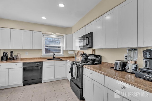 kitchen featuring a sink, light tile patterned floors, black appliances, and white cabinetry