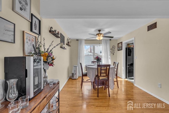 dining room with visible vents, light wood finished floors, ceiling fan, and baseboards