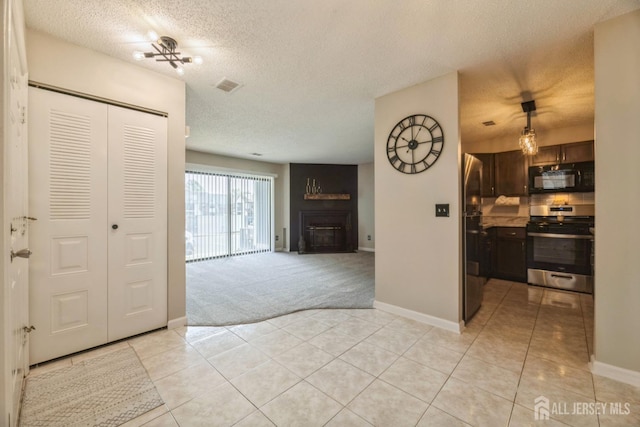 interior space with a textured ceiling, a large fireplace, baseboards, light tile patterned floors, and visible vents