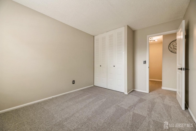 unfurnished bedroom featuring carpet floors, baseboards, a closet, and a textured ceiling