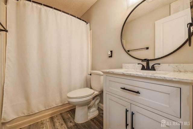 bathroom featuring vanity, a textured ceiling, wood finished floors, and toilet