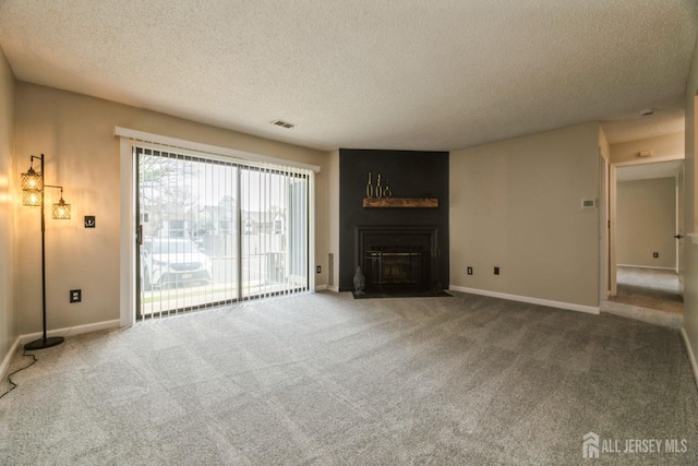 unfurnished living room featuring carpet floors, visible vents, baseboards, a textured ceiling, and a large fireplace
