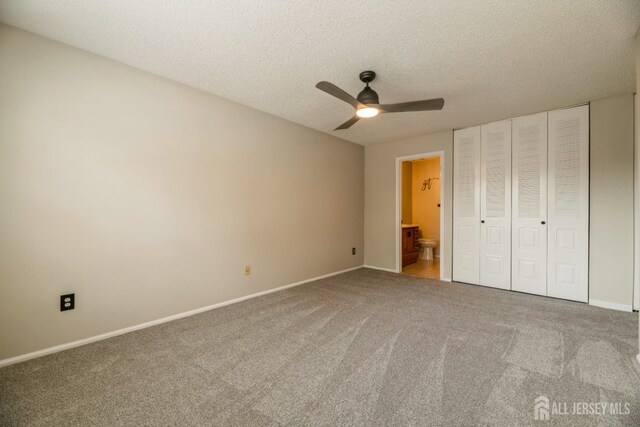 unfurnished bedroom featuring connected bathroom, a textured ceiling, carpet, baseboards, and a closet