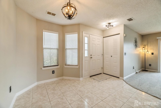 entrance foyer with visible vents, light tile patterned flooring, a chandelier, and a wealth of natural light