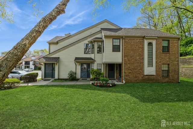 view of front facade with fence, a front lawn, and brick siding