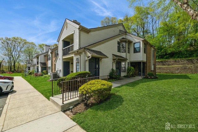 view of front of home featuring a chimney, central AC, and a front lawn