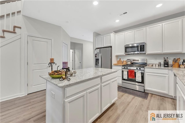 kitchen with visible vents, a center island, light wood-style floors, stainless steel appliances, and white cabinetry
