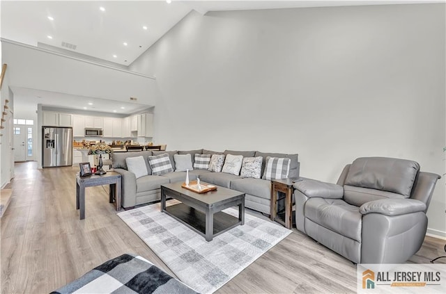 living room featuring visible vents, recessed lighting, light wood-style flooring, and high vaulted ceiling