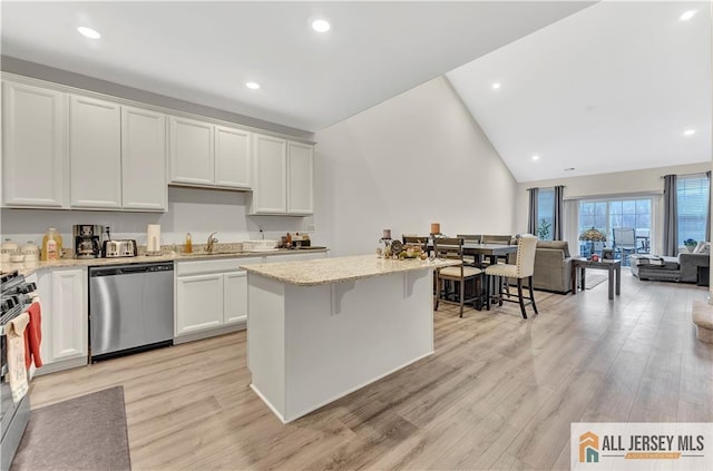 kitchen featuring open floor plan, appliances with stainless steel finishes, a sink, and light wood-style flooring