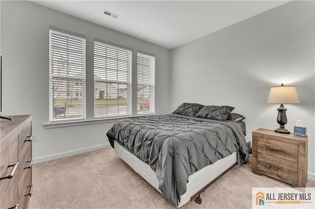 bedroom featuring visible vents, baseboards, and light carpet