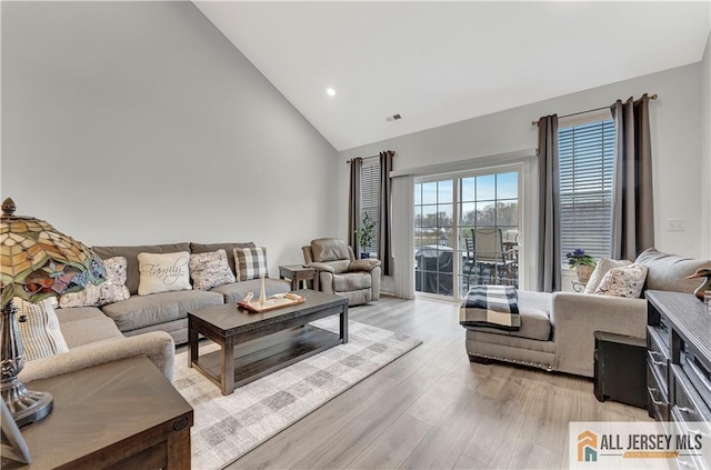 living area with high vaulted ceiling, recessed lighting, light wood-style flooring, and visible vents