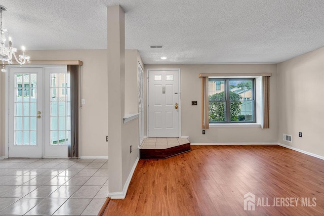 47 Covington Ct, East Brunswick, NJ 08816 - foyer entrance featuring healthy amount of natural light, a textured ceiling, a chandelier, light tile patterned floors, and french doors