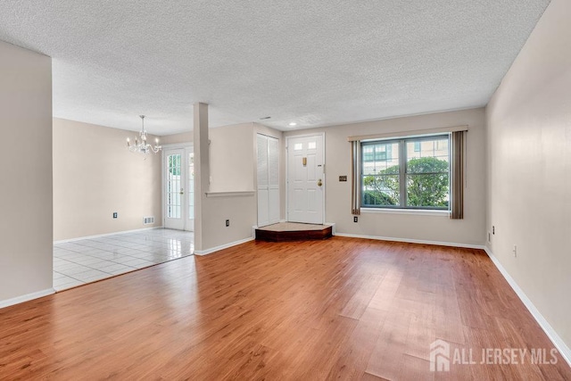 47 Covington Ct, East Brunswick, NJ 08816 - unfurnished living room with wood finished floors, a textured ceiling, and a chandelier