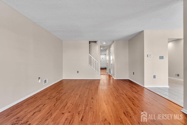 47 Covington Ct, East Brunswick, NJ 08816 - unfurnished living room with a textured ceiling, light wood finished floors, and stairway