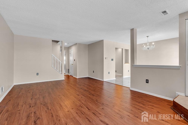 47 Covington Ct, East Brunswick, NJ 08816 - unfurnished living room with wood finished floors, a chandelier, stairs, and a textured ceiling