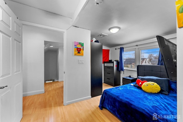 bedroom featuring visible vents, light wood-style flooring, and baseboards