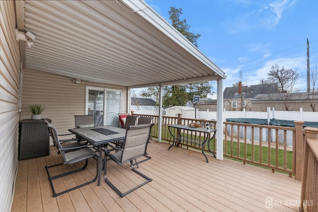 wooden terrace with outdoor dining area, an outbuilding, a fenced backyard, and a storage shed