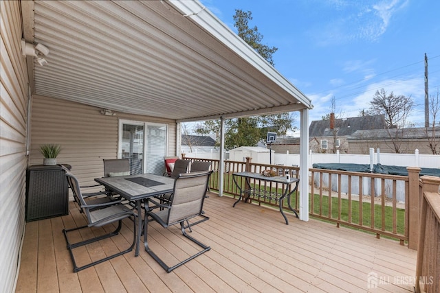 wooden deck with an outbuilding, a fenced backyard, outdoor dining space, and a storage shed