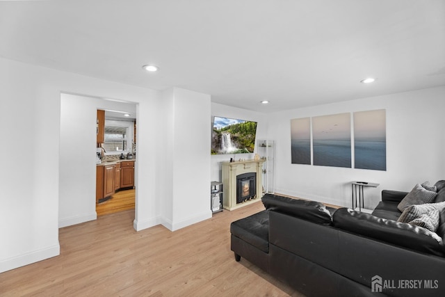 living room with baseboards, a fireplace, light wood-style floors, and recessed lighting