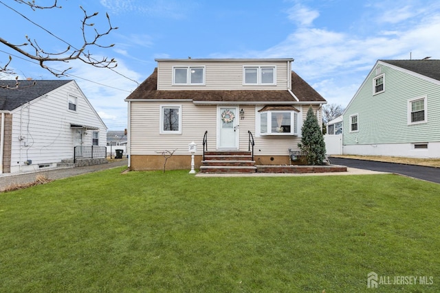view of front of home featuring a front lawn, a shingled roof, fence, and aphalt driveway