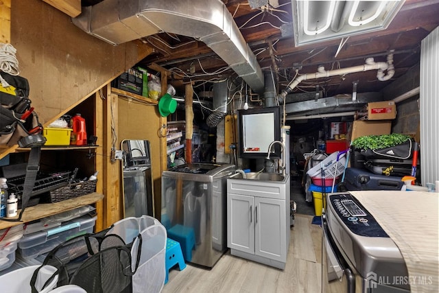 unfinished basement featuring light wood finished floors, washer and clothes dryer, and a sink