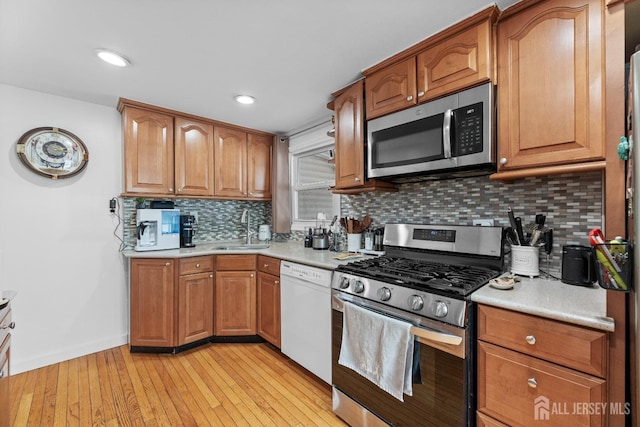 kitchen with light countertops, light wood-style flooring, appliances with stainless steel finishes, and a sink