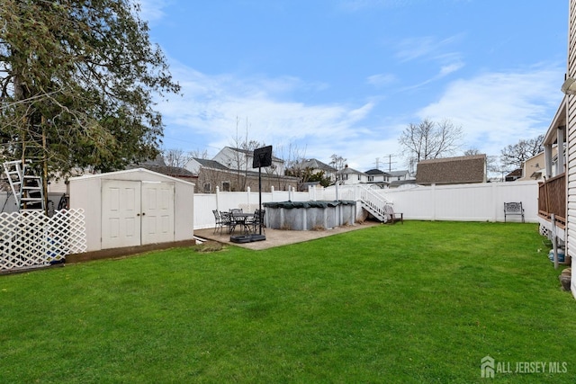 view of yard with a fenced in pool, a fenced backyard, an outdoor structure, a storage unit, and a patio