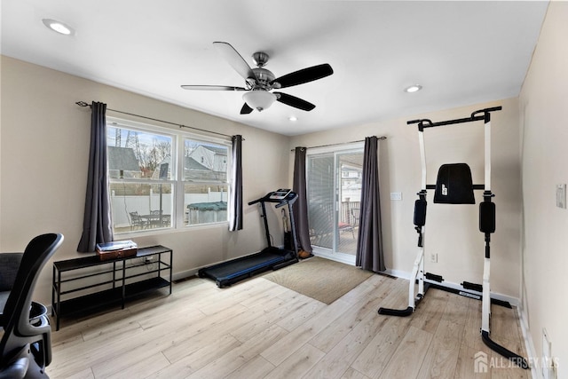 workout room featuring baseboards, light wood-type flooring, a ceiling fan, and plenty of natural light