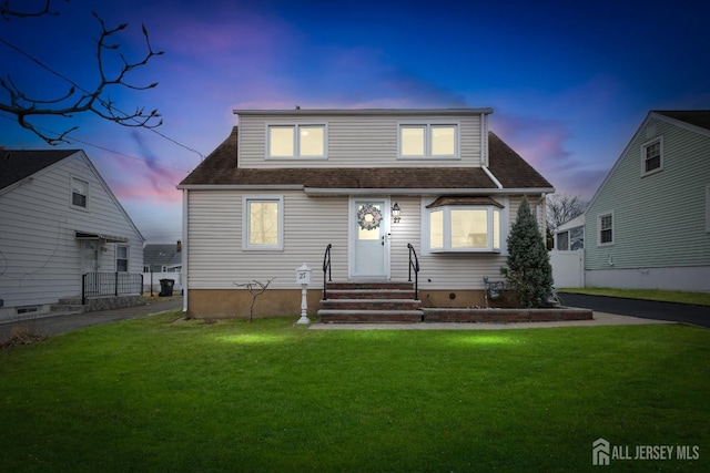 view of front of house with a lawn, a shingled roof, and fence